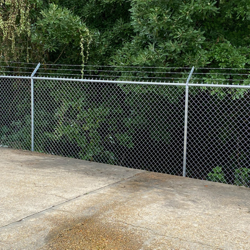 commercial chain link perimeter fence at edge of parking lot